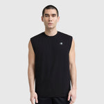A man with short dark hair wears a black Champion Sport Crewneck Muscle Tee with script logo and black shorts, standing against a plain light gray background.