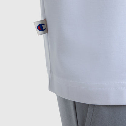 Detail of the Champion Sport Polo, C Logo in white, featuring a small logo tag on the side and styled with light gray pants for an athletic look against a plain white background.