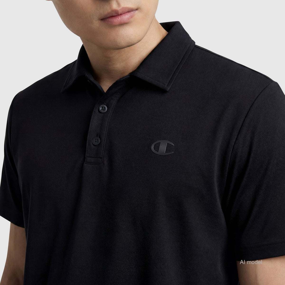 A person wearing Champion's black Sport Polo, featuring a small embroidered C Logo on the left chest, is shown from shoulders to mid-torso against a plain background. This polo delivers comfort and style for any occasion.