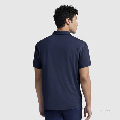 A man with short curly hair, seen from behind against a light gray background, is wearing a Champion Sport Polo with C Logo and matching pants in navy blue.