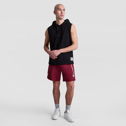 A person in a Champion Sleeveless Hoodie (C Logo), red Champion shorts, gray socks, and white sneakers stands against a plain light gray background.