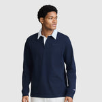 A man wearing the Champion Long Sleeve Rugby Shirt with Twill Collar and Embroidered C Logo in navy, featuring a white collar, stands against a plain light background, looking to his left with a neutral expression.