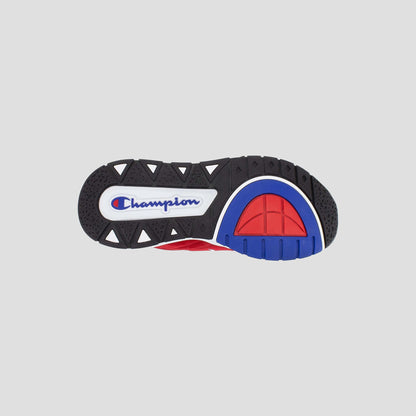 The image displays the black rubber sole of the Kids' Rally Pro sneaker by Champion, featuring blue and red accents. "Champion" is printed in blue with a red and white outline on a white oval near the heel.