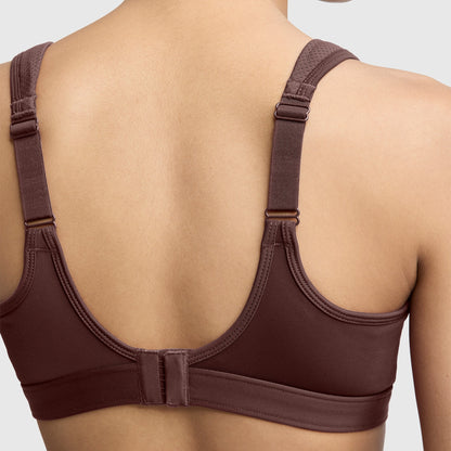 A person is shown from the back wearing the Champion Spot Comfort High-Impact Sports Bra, C Logo in brown, featuring adjustable straps and a hook-and-eye closure, set against a plain light background.