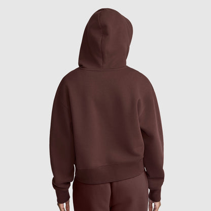 A person wearing a brown Champion Cropped Zip-Up Hoodie and matching pants stands facing away from the camera against a plain light gray background.