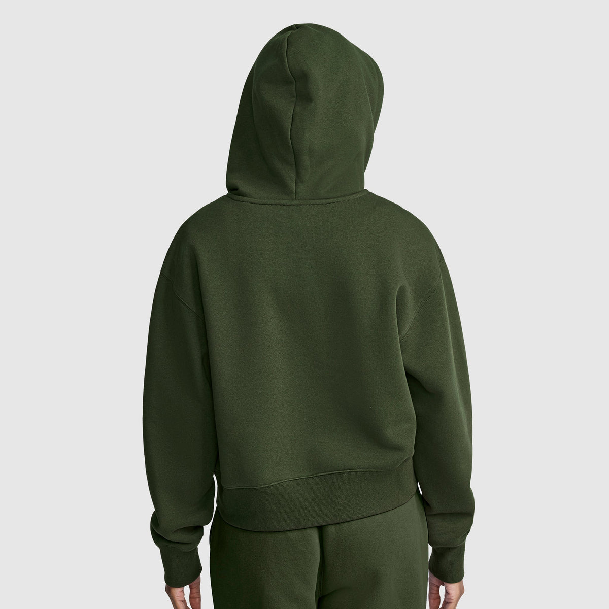 A person is wearing the Champion Cropped Zip-Up Hoodie in olive green with matching sweatpants, shown from behind against a light gray background.