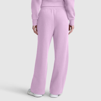 A person is shown from the back wearing Champion’s Wide Leg Fleece Sweatpants with C Logo in light purple, paired with a matching sweatshirt and white sneakers, set against a plain light gray background.