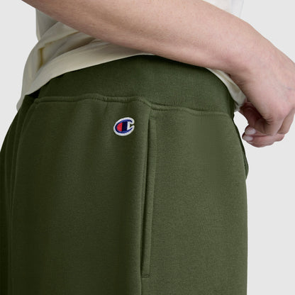 A person wears Champion Wide Leg Fleece Sweatpants with a C logo near the pocket, paired with a light-colored shirt.