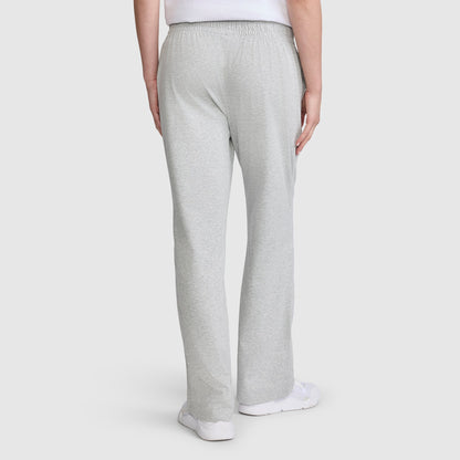 A person wearing Champion Lightweight Lounge Pants, C Logo in light gray jersey cotton and white sneakers is shown from the back, standing against a plain white background. These pants offer superior comfort and style with Champion quality craftsmanship.
