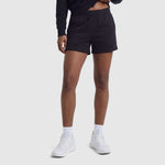 A person is seen from the waist down wearing Champion's 4" Lightweight Lounge Shorts featuring the C Logo, crafted from lightweight cotton with an adjustable waistband. The shorts are styled with a black long-sleeve top, white socks, and white sneakers, set against a plain light background.