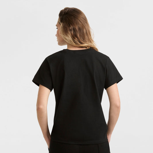 Person with light brown hair wearing a Champion Classic T-Shirt, Script Logo in plain black, facing away from the camera against a plain white background.