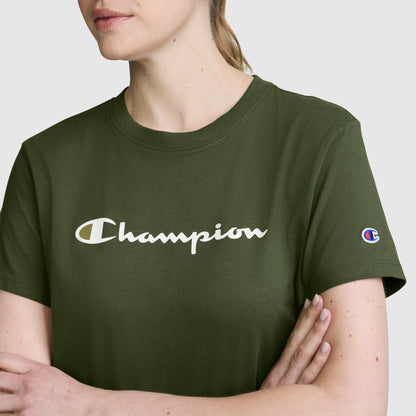 A woman stands with her arms crossed, wearing the Champion Classic T-Shirt, Script Logo in olive green. This women’s athletic shirt showcases the signature white script logo across the chest and a small Champion patch on the left sleeve, combining comfort and iconic style.