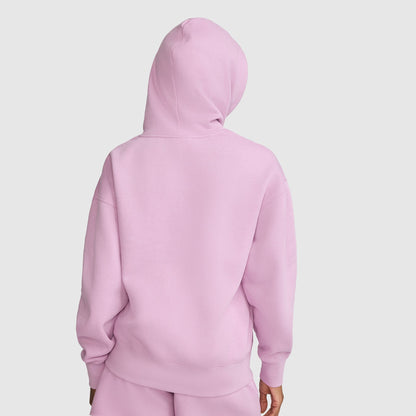 A person is shown from the back, standing against a plain white background, wearing the Champion Tonal Script Freshman Powerblend Hoodie in light pink with matching pants.