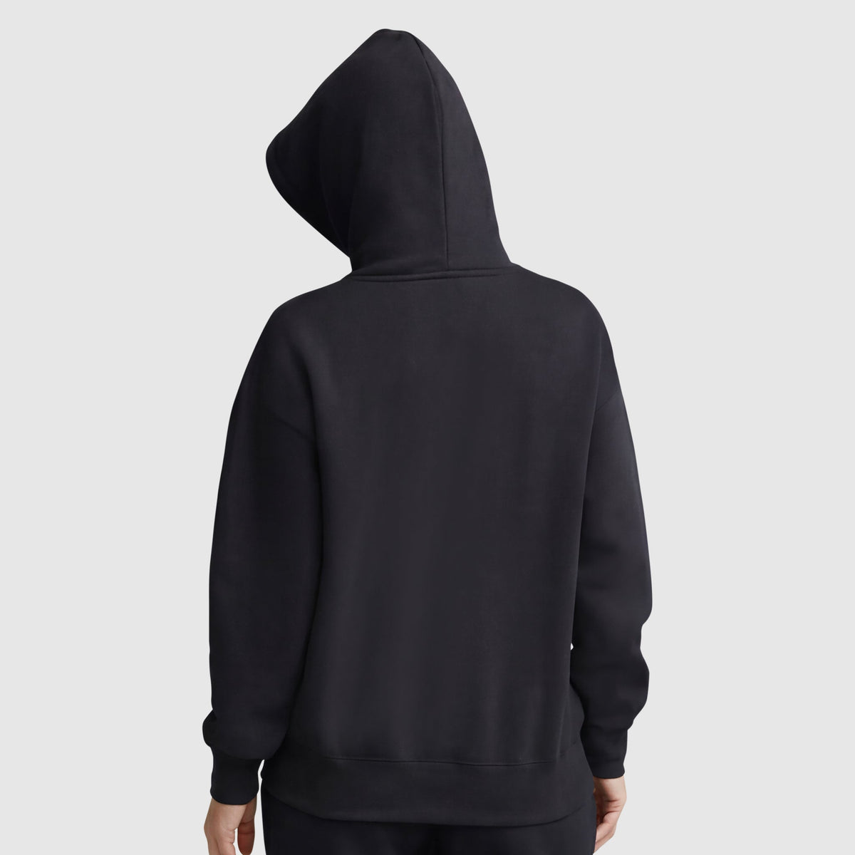 A person wearing a plain black Champion Powerblend Freshman Hoodie, C Logo, with the hood up and facing away from the camera against a light gray background. Only the back of this cozy fleece hoodie and the person's hands are visible.