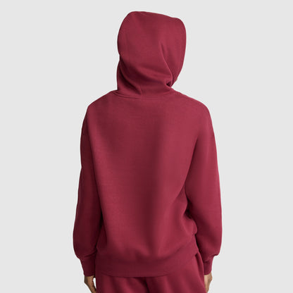 A person wearing a red Champion Small C Freshman Powerblend Hoodie and matching pants, seen from behind against a plain light gray background, showcases the comfort and style of this women’s hooded sweatshirt.