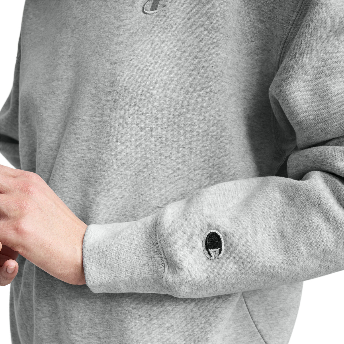 Wearing the Champion Powerblend Crewneck with a small "C" logo embroidered on the chest and sleeve, the focus is on their hands, upper body, and the comfort of its midweight fleece fabric.