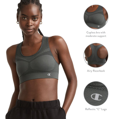 A woman models the Champion Seamless Racerback Sports Bra in dark gray, designed for moderate support. Three close-up shots highlight the supportive front panel, breathable seamless racerback, and a reflective Champion logo. She stands with her hands in her pockets and a slight smile.
