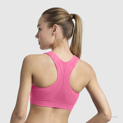 A woman with a ponytail is seen from the back wearing the Champion Seamless Racerback Sports Bra in bright pink, set against a light gray background.
