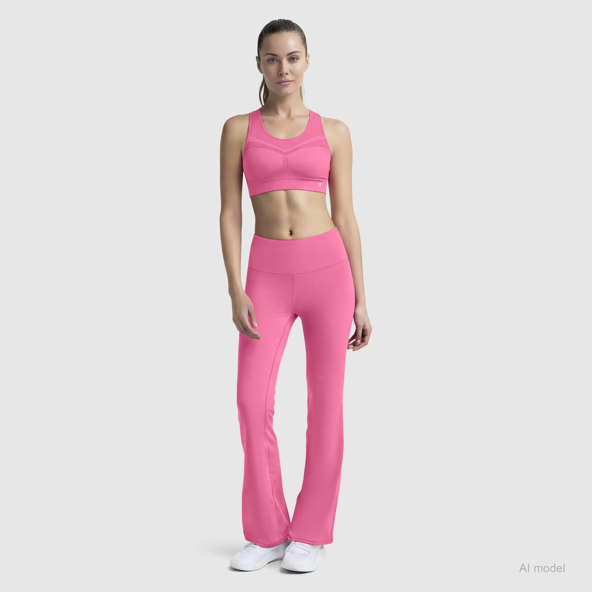 A woman in a Champion Seamless Racerback Sports Bra and flared leggings stands facing forward, long hair tied back, wearing white athletic shoes against a plain light gray background.