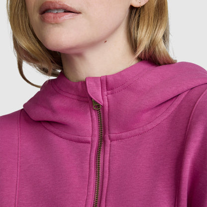 A close-up of a woman wearing a bright pink Champion Training Half-Zip Fleece Hoodie. The image highlights the lower part of her face and upper chest, focusing on the hoodie’s zipper and neckline.