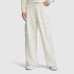 A person is wearing the Champion Fleece Cargo Training Pant for women in a loose, off-white fit with side pockets, styled with a coordinating sweatshirt and white sneakers, standing against a plain white background.