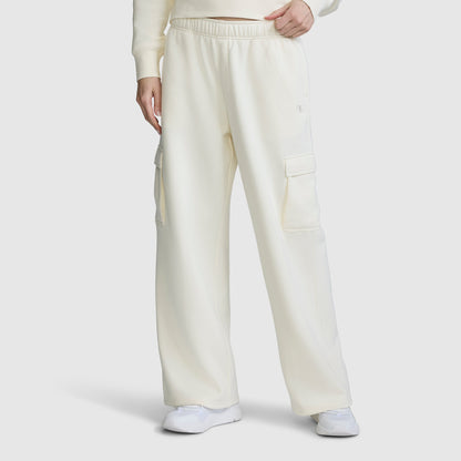 A person is wearing the Champion Fleece Cargo Training Pant for women in a loose, off-white fit with side pockets, styled with a coordinating sweatshirt and white sneakers, standing against a plain white background.