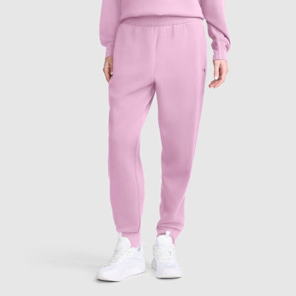 A person wearing the Champion Taper Leg Jogger with Zippers in light pink, paired with a matching pink sweatshirt and white sneakers, stands against a plain light gray background.