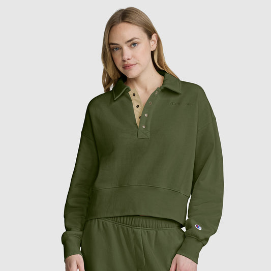 A woman with long blonde hair wears the Champion Fleece Training Polo in olive green, featuring a collar and matching pants, as she stands against a plain light gray background.