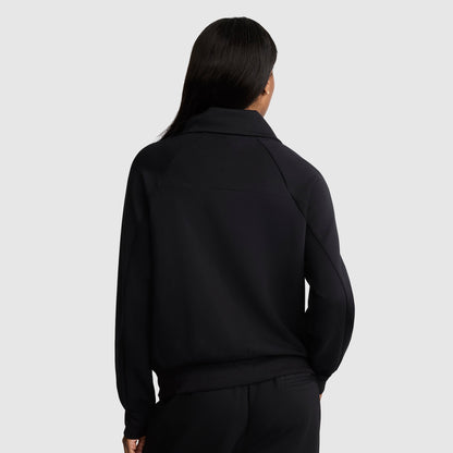 A person with long, dark hair is shown from the back, wearing a black Champion Quarter-Zip Pullover and matching black pants against a plain light gray background.