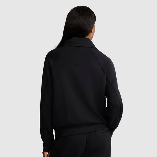 A person with long, dark hair is shown from the back, wearing a black Champion Quarter-Zip Pullover and matching black pants against a plain light gray background.