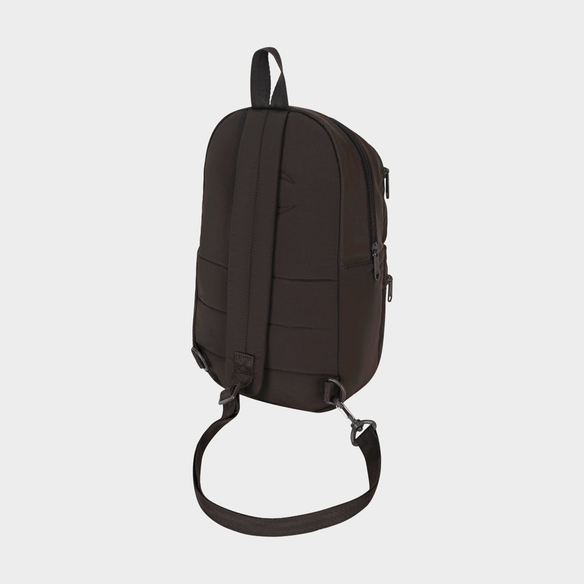 A Champion Explore Sling backpack in black, displayed from the back against a plain white background. This bag features a top handle, adjustable shoulder strap, secure zipper closures, and a sleek minimalist design—ideal for compact carrying when you want to travel light.