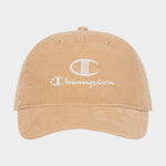 Introducing the Pursuit Corduroy Adjustable Cap by Champion—a tan corduroy baseball cap featuring the word “Champion” and a bold C logo embroidered in white on the front. Designed with a curved brim and an adjustable snapback closure, this cap offers timeless style and personalized comfort. It is showcased against a plain background.