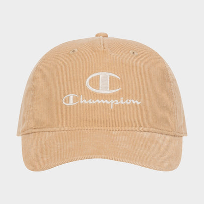 Introducing the Pursuit Corduroy Adjustable Cap by Champion—a tan corduroy baseball cap featuring the word “Champion” and a bold C logo embroidered in white on the front. Designed with a curved brim and an adjustable snapback closure, this cap offers timeless style and personalized comfort. It is showcased against a plain background.