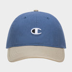 The Champion Briggs Washed Cotton Twill Adjustable Baseball Cap in blue features a beige brim and an embroidered white C logo on the front, displayed against a plain white background.
