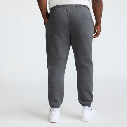 A person in a white T-shirt, Champion Powerblend Sweatpants with Cinched Bottom and C Logo (Big & Tall), and white sneakers stands with their back to the camera against a plain light background.