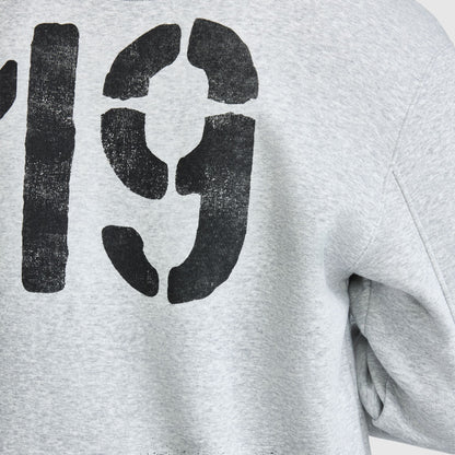 Close-up of a grey Champion Fleece Baseball Jacket with the black stencil-style number 19 printed on the back.