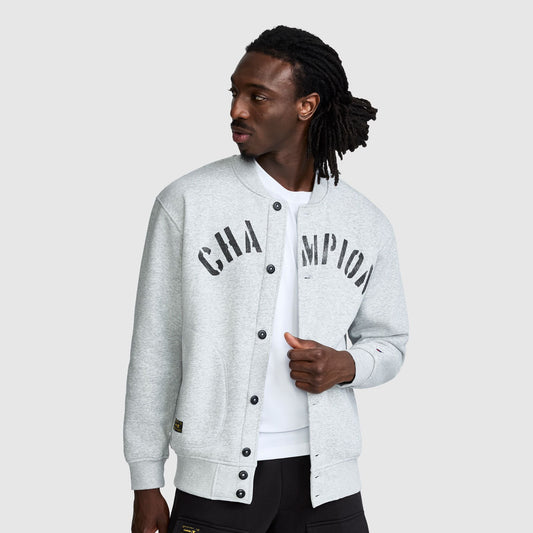 A man wears a light gray Champion Fleece Baseball Jacket with a varsity-style logo across the chest.