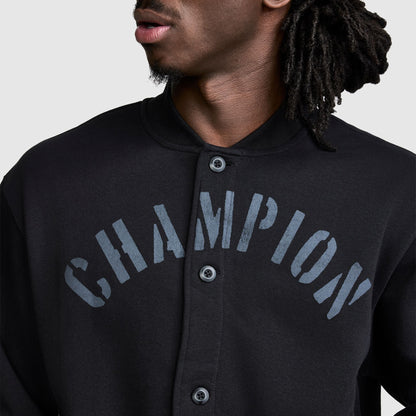A person wearing a black Champion Fleece Baseball Jacket, featuring large, faded CHAMPION lettering across the chest for a vintage athletic look. Only the lower half of their face and upper torso are visible.