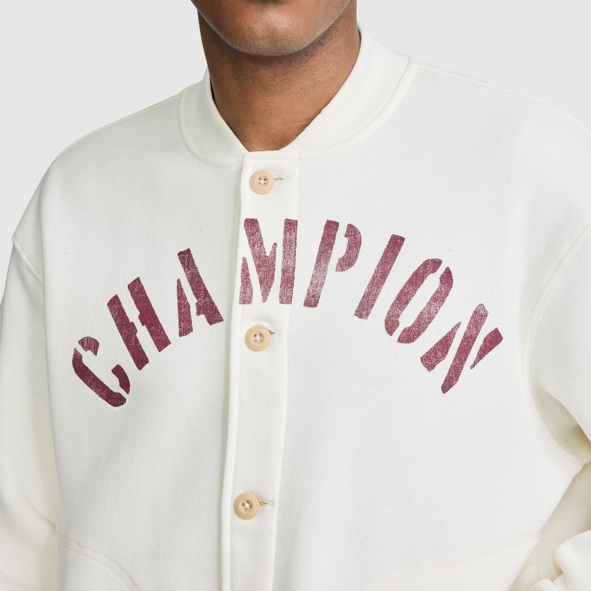 Off-white button-front Champion Fleece Baseball Jacket with the word CHAMPION in distressed red lettering across the chest.