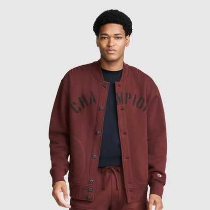 A person wearing a maroon Champion Fleece Baseball Jacket with black lettering across the chest.