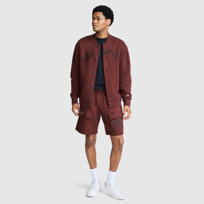 A person wearing a maroon Champion Fleece Baseball Jacket with text across the chest and matching cargo shorts with a number on the leg.