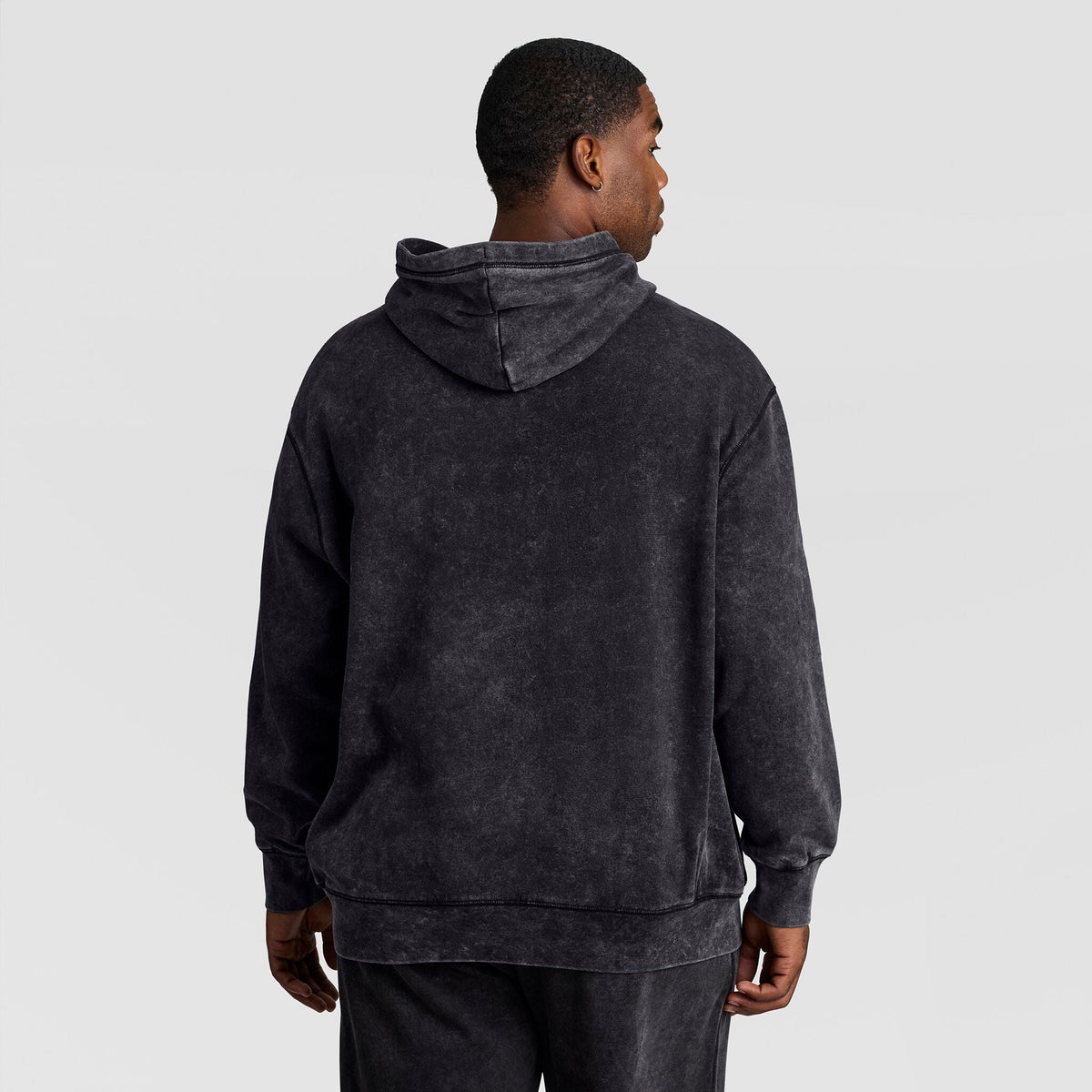 A person seen from behind wearing a black Mineral Wash Pullover Hoodie, C Patch Logo by Champion.