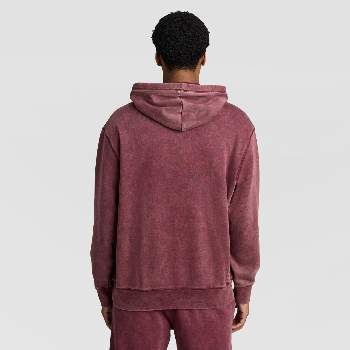 A person seen from the back wearing a maroon Mineral Wash Pullover Hoodie, C Patch Logo by Champion.