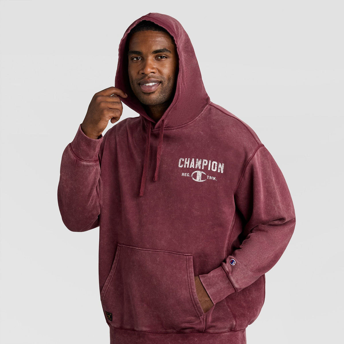 A man wearing a dark red Mineral Wash Pullover Hoodie, C Patch Logo with a large chest graphic.