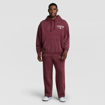 A man wearing a burgundy mineral wash Mineral Wash Pullover Hoodie, C Patch Logo and matching sweatpants.