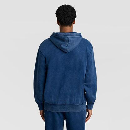 Back view of a person wearing a blue Mineral Wash Pullover Hoodie, C Patch Logo with the hood up.