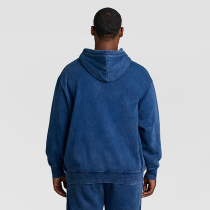 Back view of a person wearing a blue Mineral Wash Pullover Hoodie, C Patch Logo, featuring a vintage, faded mineral-wash finish.