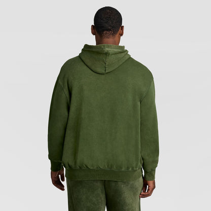 A person seen from behind wearing an olive green Mineral Wash Pullover Hoodie, C Patch Logo by Champion.