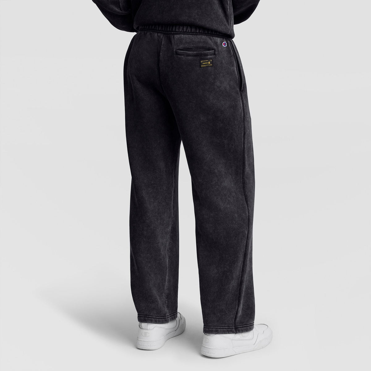 Back view of black Mineral Wash Open Hem Pant by Champion, featuring a small patch pocket and logo on the rear.