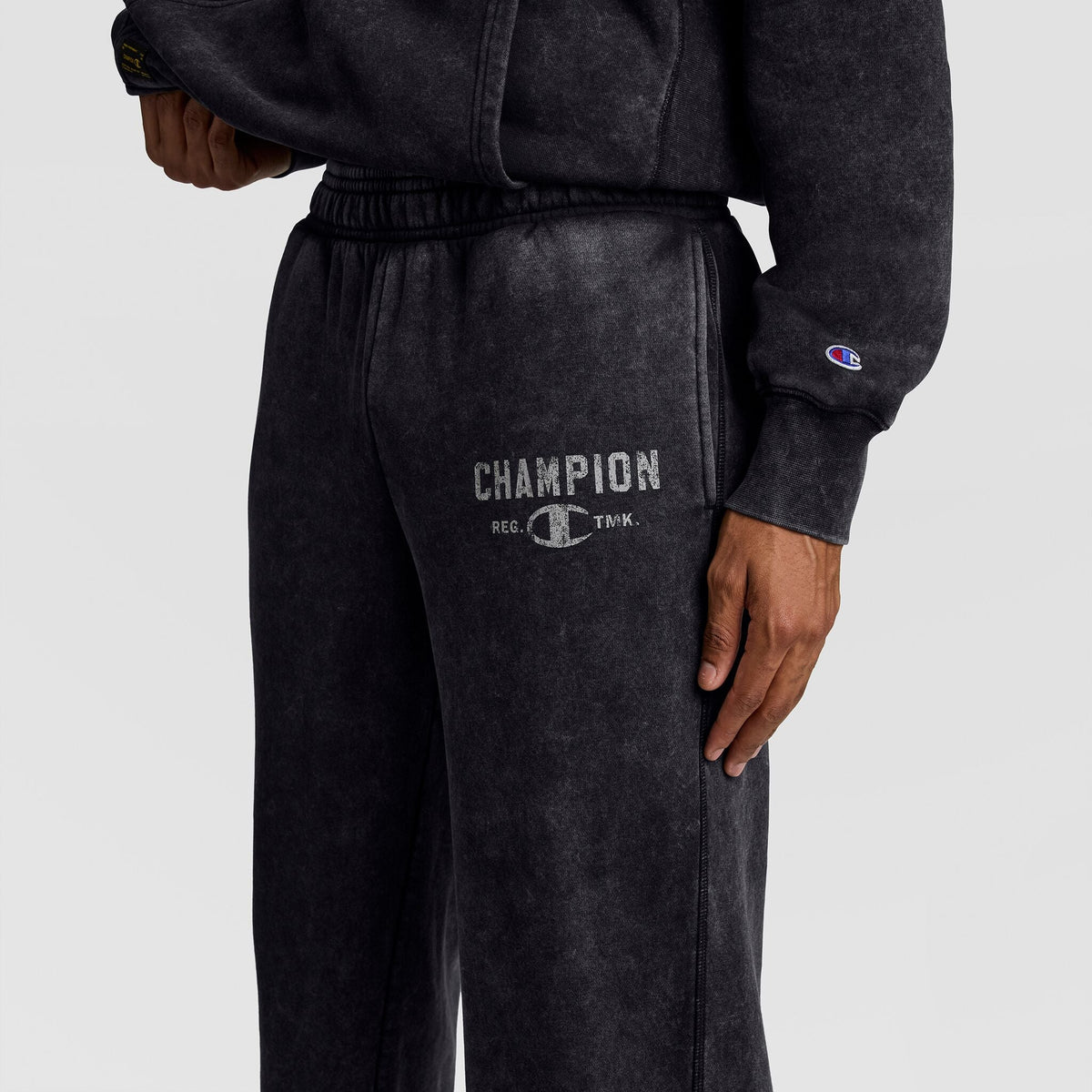Black mineral wash Champion Mineral Wash Open Hem Pant featuring a distressed logo on the thigh, designed as vintage-look athletic fleece pants.